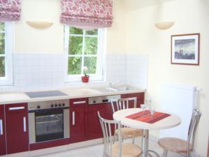 欧巴德伍斯图Aalkoje Ostseebad Wustrow的厨房配有红色橱柜和桌椅
