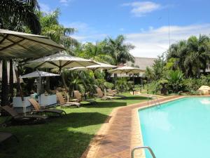 MatsaphaSummerfield Botanical Garden & Exclusive Resort的毗邻度假酒店的带椅子和遮阳伞的游泳池