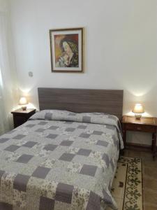加拉蒂纳Casa vacanze Marilena的卧室配有1张床和2张桌子,墙上挂着1张照片