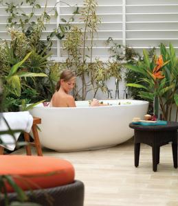 圣地亚哥勒奥伯奇德尔马水疗度假酒店的坐在植物环绕的浴缸中的女人