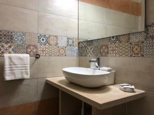 切萨雷奥港B&B MiMì的浴室设有白色水槽,墙上铺有瓷砖。