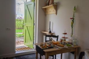 Uddel't Rheebokje的一间设有桌子、面包和绿门的房间