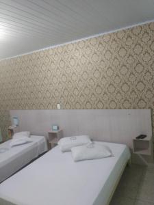 瓜鲁柳斯Cumbipar King Hotel的墙上的房间里设有两张床