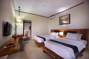 吉利特拉旺安ASTON Sunset Beach Resort - Gili Trawangan的一间卧室配有两张床、一张桌子和一台电视。