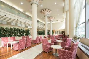 冈山Ark Hotel Okayama -ROUTE INN HOTELS-的大堂,大楼内摆放着粉红色的椅子和桌子