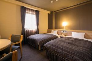 冈山Ark Hotel Okayama -ROUTE INN HOTELS-的酒店客房设有两张床、一张桌子和一个窗户。