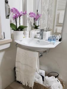 科尔马诺Appartamento Via Acquati 12 - Monolocale 2的浴室设有鲜花和毛巾的盥洗盆
