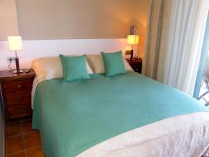 安波拉Lirio的一间卧室配有一张带绿床单和枕头的床。