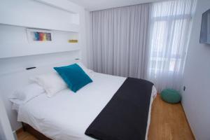 大加那利岛拉斯帕尔马斯Superb Apartament Canteras的卧室配有白色床和蓝色枕头