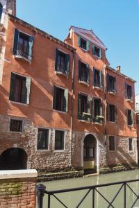 威尼斯里阿尔托圣利奥大厅公寓的运河上带窗户的红砖建筑