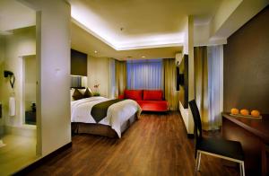 雅加达ASTON Pluit Hotel & Residence的酒店客房,配有一张床和一张红色的沙发