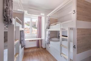 里斯本Goodmorning Solo Traveller Hostel的客房设有白色双层床和窗户。