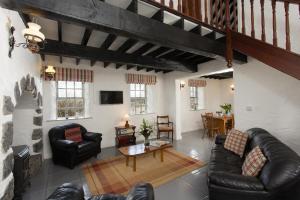 戈尔韦Dunguaire Thatched Cottages的客厅配有黑色皮革家具和桌子