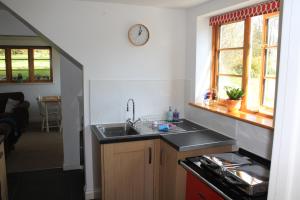 耶尔弗顿The Dartmoor Linhay的厨房配有水槽和墙上的时钟