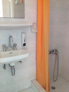 利瓦迪奥ELEFTHERIA rooms的浴室设有橙色淋浴帘,位于水槽旁