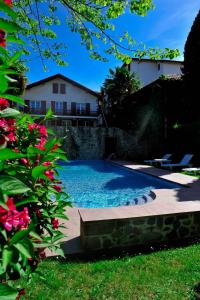 圣让皮耶德波尔比利牛斯酒店的庭院内的游泳池,后面有房子
