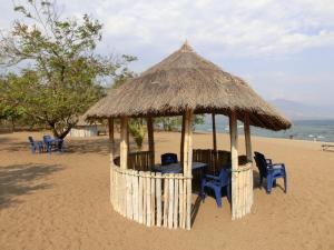 Matema BeachMatema Lake Shore Resort的海滩上配有桌椅的凉亭