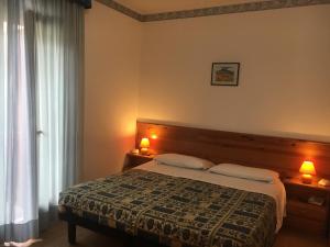 塔尔维西奥国际酒店 的一间卧室配有一张床、两盏灯和一个窗户。