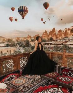 格雷梅格雷梅洞穴酒店的坐在带热气球的阳台的身着黑色衣服的女人