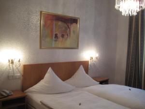 卡尔斯鲁厄马克格拉弗勒酒店的一间卧室配有一张带白色床单和吊灯的床。