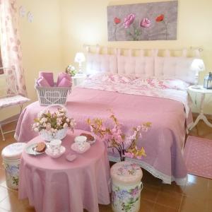 TuiliB&b il Giardino da Pina的一间卧室配有粉红色的床和两张鲜花桌