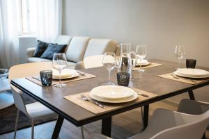 特伦托Cinquanta4 Charme Apartment的餐桌,配有盘子和酒杯