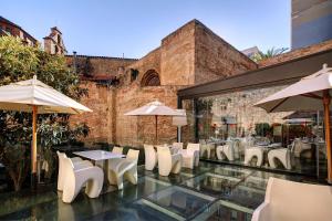 巴塞罗那奥利维亚宫酒店的一间设有白色椅子、桌子和遮阳伞的餐厅