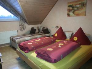 鲁斯特Ferienwohnungen - Gästehaus Gertrud Moog-的两张床铺,房间配有红色和黄色枕头