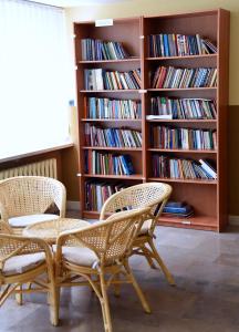 华沙多布勒密斯瑞可了西尼旅馆的书架的房间设有两把椅子和一张桌子