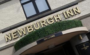 EllonNewburgh Inn的建筑前方的标志,带有欢迎标志