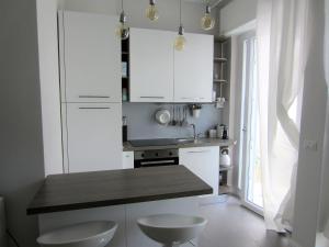 里米尼New & modern apartment on the sea的厨房配有白色橱柜和带2张凳子的台面