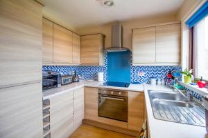 克雷尔Beach House Walk - Crail - Home from Home的厨房配有木制橱柜,墙壁上铺有蓝色瓷砖。