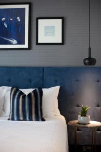 悉尼莫斯拜克斯酒店的一间卧室配有一张带蓝色床头板的床和一张桌子