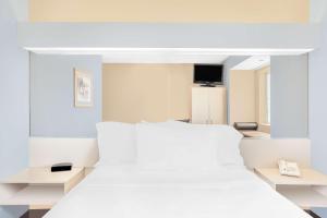 克利尔莱克明湖麦克洛特套房酒店的白色的卧室配有白色的床和电视。