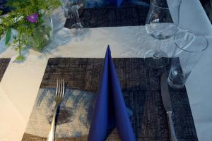 巴尔特鲁姆菲森纳酒店的一张带蓝色餐巾的桌子,一张叉子和刀子