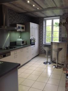 Pierrefitte-en-CinglaisL' ancien pressoir 2的厨房配有白色橱柜和带凳子的台面