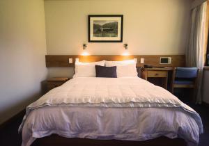 圣阿诺Alpine Lodge的一间卧室配有一张带白色床单的大床