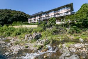 下关Ichinomata Onsen Kanko Hotel的河边的建筑物,有建筑物