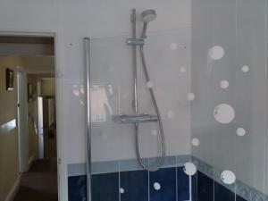 布里德灵顿圣希尔达宾馆的浴室铺有蓝色和白色瓷砖,设有淋浴。