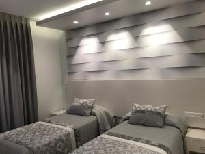 马德里阿波罗公寓的一间设有两张床和灯光的墙壁的房间