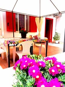 那不勒斯Garden House Airport的庭院配有桌子和一些粉红色的鲜花