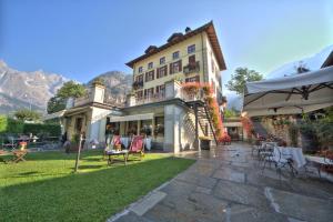 库马约尔Villa Novecento Romantic Hotel - Estella Hotel Collection的一座大建筑,设有桌椅庭院