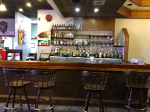McCrearyAgassiz Park Lodge的酒吧设有三把酒吧凳和瓶装酒精饮品