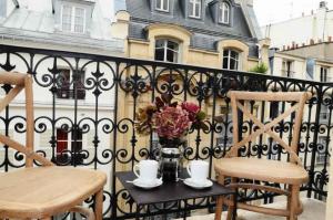 巴黎卡玛汀64号公寓酒店的阳台配有两把椅子和一张花瓶桌子。