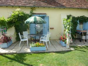 ChézellesLavender Cottage的庭院配有桌椅和遮阳伞。
