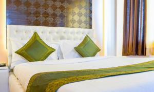 浦那Treebo Trend Naunidh Suites的卧室配有带绿色枕头的白色床