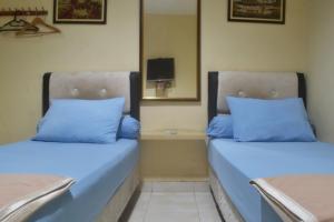 雅加达Pondok Seruni Kemanggisan Jakarta的配有蓝色枕头的客房内的两张床