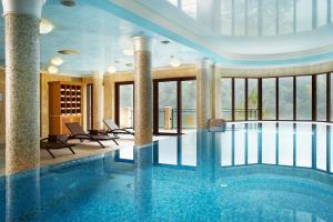 卡罗维发利Retro Riverside Wellness Resort的一座大型游泳池,位于一座带大窗户的建筑内