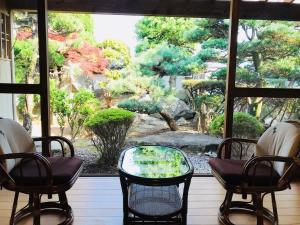 熊野市沃家池凯旅馆的窗户享有花园景色,配有椅子和桌子