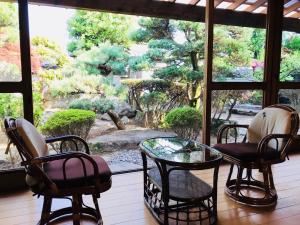 熊野市沃家池凯旅馆的一间带椅子、玻璃桌和窗户的房间
